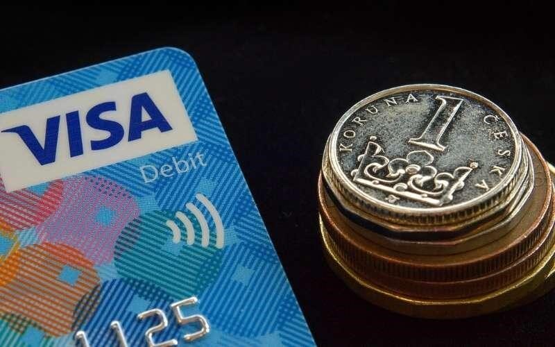 ویزا کارت فیزیکی در کنار سکه ها برای پرداخت